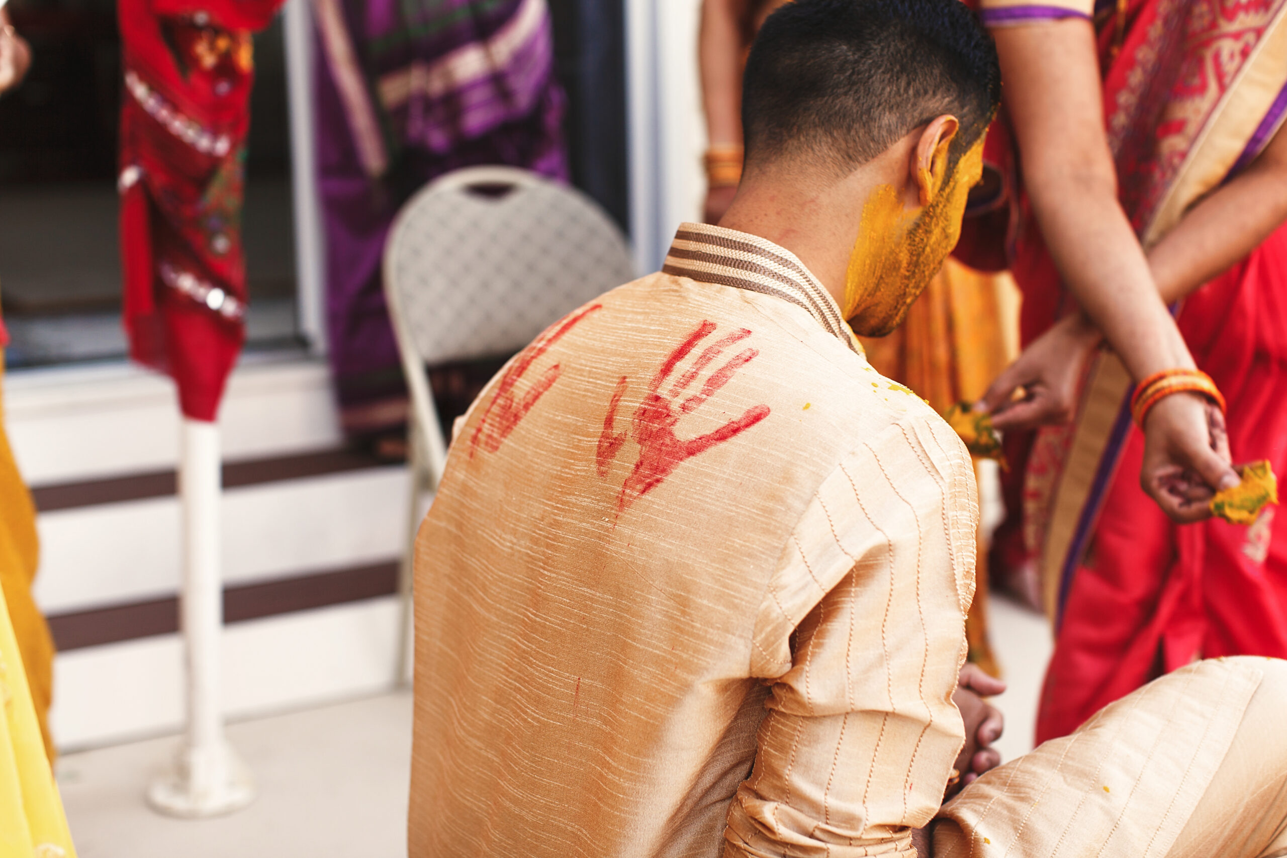 Prints of red palms put over the shirt of Indian groom sitting o